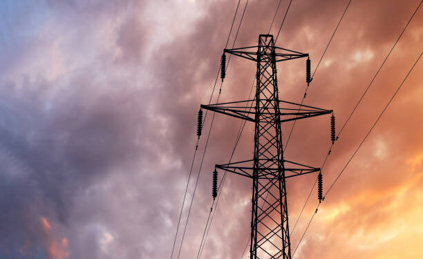 Detail of a British Style Electricity Pylon and suspended electic cables against a Blue Cloudy Sky