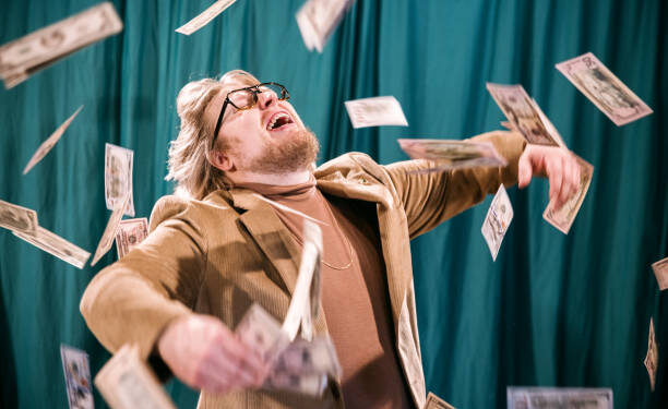 Vintage looking Caucasian man with late 1970's or early 1980's fashion styling. He smiles with joy as cash falls down in the air around him.  Turtleneck with a blazer and gold chain.