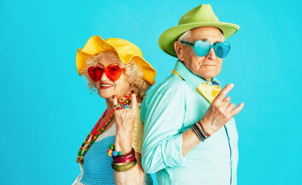 Beautiful senior old couple wearing fancy party clothes acting in studio on a colored background. Conceptual image about third age and seniority, old people feeling young inside.